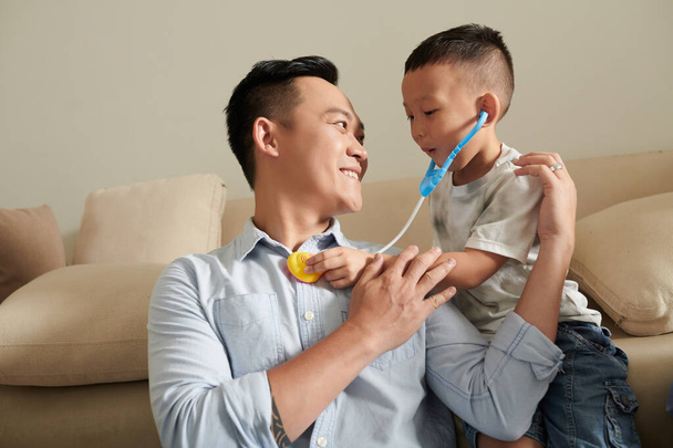 Маленька дитина слухає серцебиття свого тата з іграшковим стетоскопом - Фото, зображення