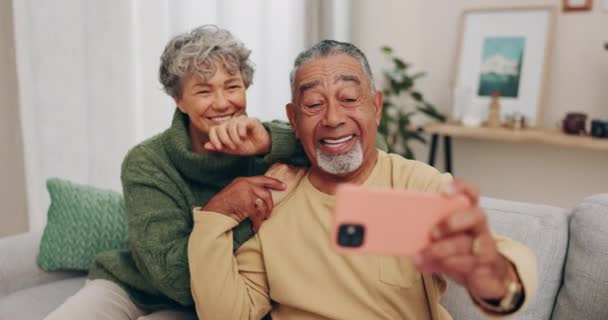 Šťastný starší pár, gauč a selfie s úsměvem, držící se za ruce nebo relaxovat na blogu, příspěvek a láska k lepení doma. Starý muž, starší žena a pohovka pro mem, sociální sítě a fotografie v domě. - Záběry, video