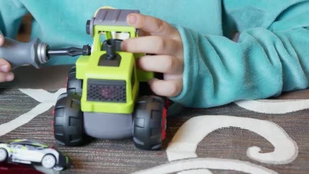 Cute boy elf montażu zabawek dla dzieci przed choinką. Wysokiej jakości materiał 4k - Materiał filmowy, wideo