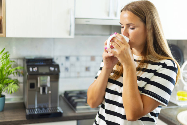 Houkutteleva nainen nauttii tuoretta kahvia keittiössä aamulla. - Valokuva, kuva