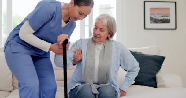 Senior, nő és nővér sétapálcával, segítség és támogatás a kanapén a nappaliban az idősek otthonában. Idősek, személyek és gondozók a hospice-i mobilitás segítésével, részvéttel és szolgálatával. - Felvétel, videó