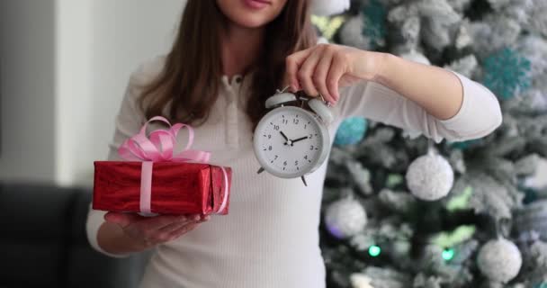 Женщина-покупатель держит подарочную коробку и будильник. Рождественские продажи и скидки - Кадры, видео