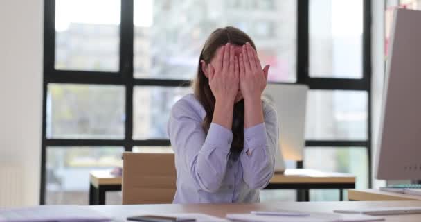 Νεαρή υπάλληλος γραφείου γυναίκα κρύβεται πρόσωπο με τα χέρια. Συναισθήματα αβεβαιότητας στο χώρο εργασίας - Πλάνα, βίντεο