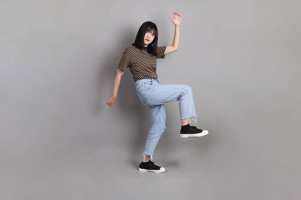 La longueur totale de la jeune femme asiatique adulte debout sur le fond gris. - Photo, image
