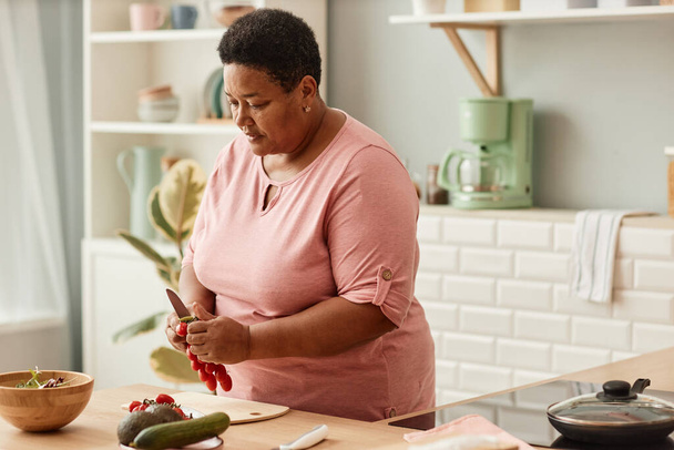居心地の良い家庭のキッチンで健康的なサラダを調理する上級黒人女性の肖像画をウエスト, コピースペース - 写真・画像