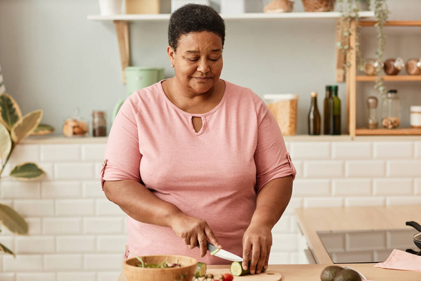 taille omhoog portret van senior zwarte vrouw snijden groenten tijdens het koken in gezellige huiskeuken, kopieer ruimte - Foto, afbeelding