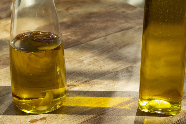 пляшка домашньої ароматизованої оливкової олії на дерев'яному столі - Фото, зображення