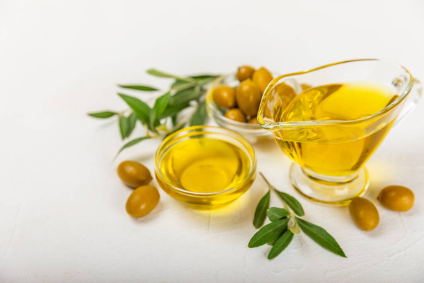 Olive oil in a bottle on a white texture background. Oil bottle with branches and fruits of olives. Place for text. copy space. cooking oil and salad dressing. - Photo, Image