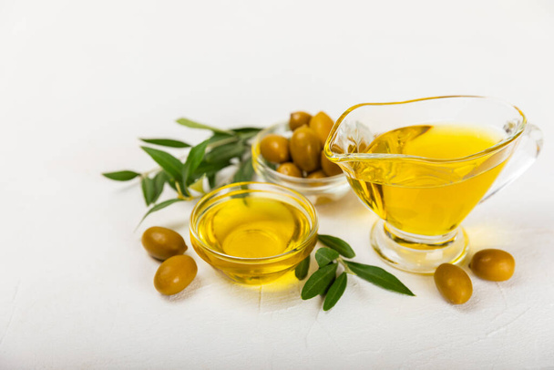 Olivenöl in einer Flasche auf weißem Hintergrund. Ölflasche mit Zweigen und Früchten von Oliven. Platz für Text. Kopierraum. Speiseöl und Salatdressing. - Foto, Bild