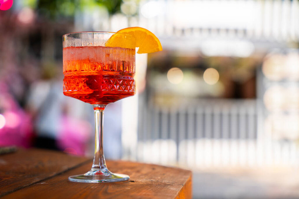Dva perlivé aperitiv koktejly s oranžovou ozdobou, na dřevěném povrchu tyče, s bokeh světly na pozadí - Fotografie, Obrázek