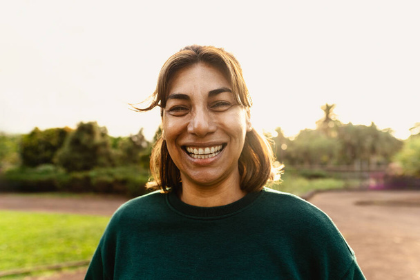 Glückliche Latino-Frau hat Spaß und lächelt in die Kamera in einem öffentlichen Park - Foto, Bild