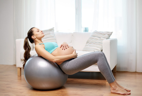 happy pregnant woman exercising on fitball at home - Foto, afbeelding
