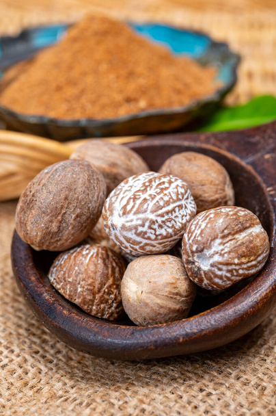 Tasty winter spice whole dried and ground powder nutmeg, used as an ingredient in many dishes, eggnog, potato, mulled wine, close up - Photo, Image