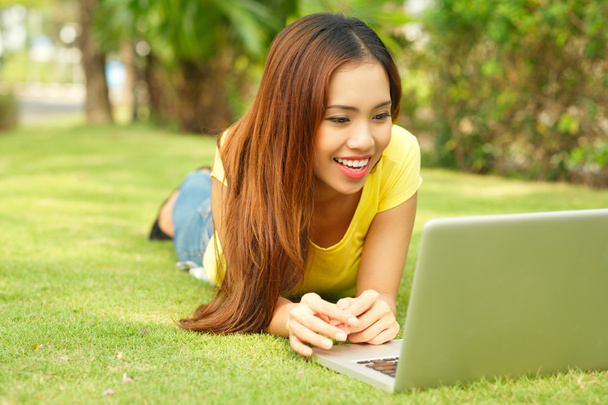 Girl with laptop lying on lawn - Photo, Image