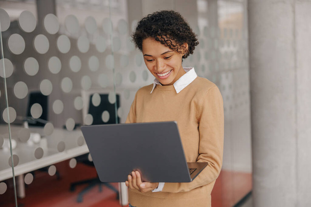 Kaunis nainen freelancer työskentelee kannettavan tietokoneen seisoessaan moderni coworking tausta - Valokuva, kuva