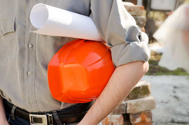  Человек держит защитный строительный шлем и проект в h
 - Фото, изображение