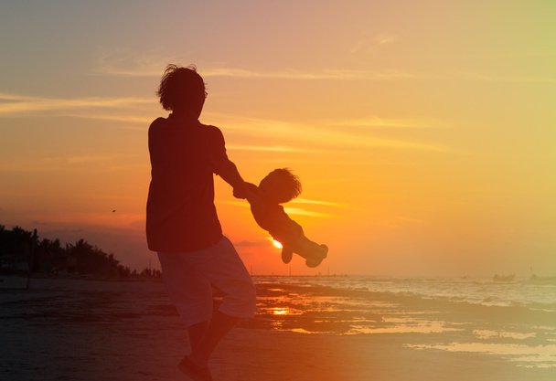 isä ja pieni poika leikkivät auringonlaskun aikaan
 - Valokuva, kuva