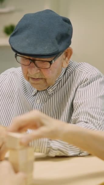 Video con viaje lateral de tres personas mayores jugando con juegos de mesa de habilidad de madera en un hogar de ancianos - Metraje, vídeo