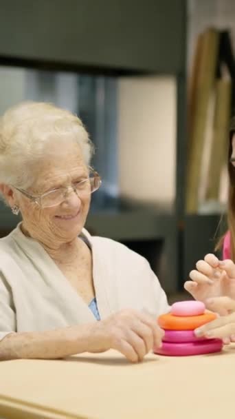 Video de una enfermera ayudando a una mujer mayor a resolver un juego de habilidad en una geriatría - Metraje, vídeo