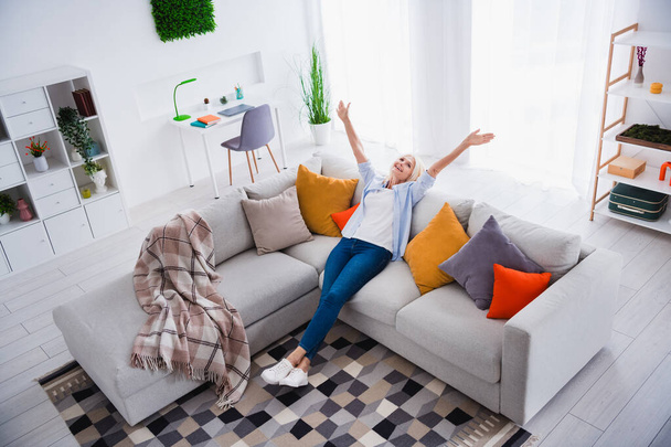 Photo portrait of attractive pensioner woman raise hands have fun sit sofa living room modern interior decoration. - Foto, Imagem