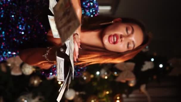 Belle femme reçoit un don de beaucoup d'argent. Une femme jette de l'argent sur un arbre du Nouvel An. Cadeaux de Noël concept. Vidéo verticale - Séquence, vidéo