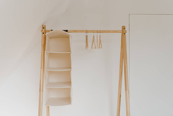 Lege hangers op vloerhanger over witte muur. Minimalistisch woonconcept met garderobe. Online modewinkel, online winkelachtergrond - Foto, afbeelding