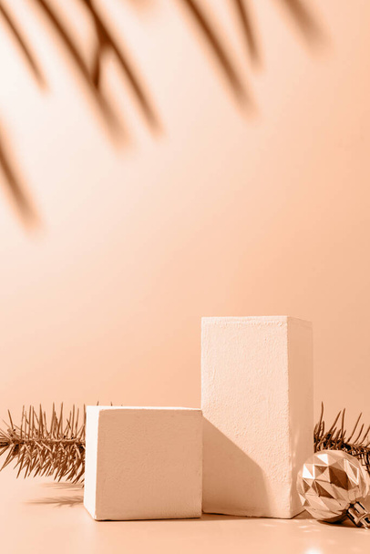 Eine minimalistische Podiumsszene mit Weihnachtskugeln und Tanne auf hellblauem Hintergrund. Laufsteg zur Präsentation von Produkten und Kosmetika. Farbe des Jahres 2024: Peach Fuzz. - Foto, Bild