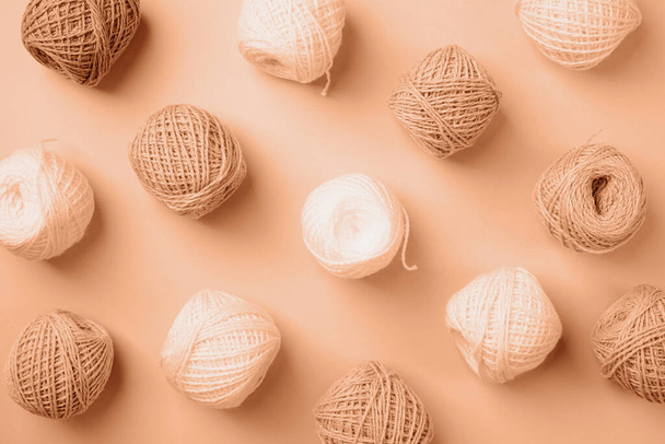 Color del año 2024: Melocotón Fuzz. lana de hilo de color pastel y beige sobre fondo beige, vista superior plana laico. Patrón de punto - Foto, imagen