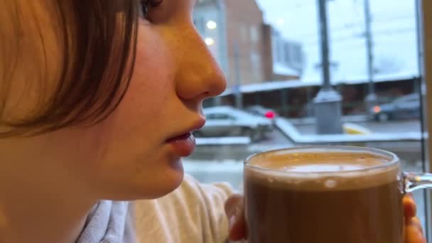 ガールフェイスフリックル ホットチョコレートココアを飲む 冬の秋の寒い運転都市車の背景に対して牛乳を飲む おいしい天然製品アロマティックティーンエイジャー. カフェの若い実在の人物 - 映像、動画