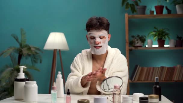 kudrnatý arabský chlap aplikovat obličejovou masku a krém na ruce při pohledu do zrcadla dělá kosmetické procedury doma. Estetická medicína koncepce kosmetických výrobků pro péči o pleť. Kopírovat prostor - Záběry, video