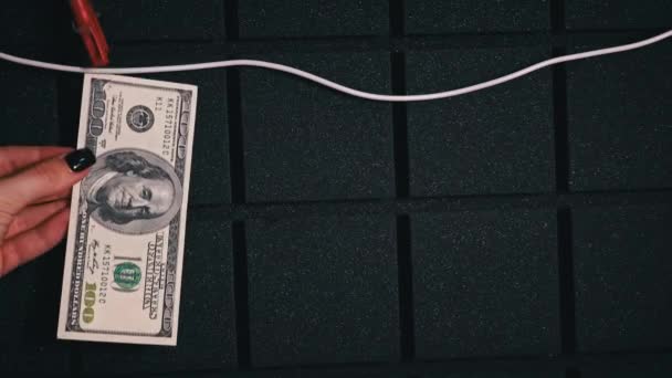 Geschäftsmann hängt Dollar mit Wäscheklammern an einem Seil. Korruption und Geldwäsche. Dollarscheine hingen an einem Seil. - Filmmaterial, Video