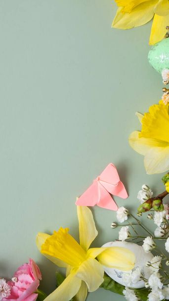 Jarní květiny a velikonoční vejce hraničí na zeleném pozadí s kopírovacím prostorem. Šablona velikonočního přání. - Fotografie, Obrázek