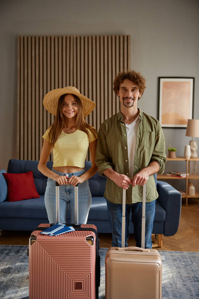 Happy family couple going for trip posing with packed luggage suitcases at home. Ready for vacation and romantic voyage start concept - Photo, Image