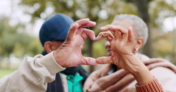 Senior, láska a pár srdcových rukou pro důvěru, podporu a péči společně ve venkovním lese, parku nebo přírodě. Ráno, muž a starší žena na dovolené v důchodu nebo dovolenou v lese pro romantiku. - Záběry, video