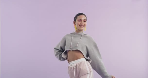 Dance, smile and face of woman in studio with music, playlist or album for entertainment. Party, happy and portrait of young female person from Canada with wave gesture with song by purple background. - Footage, Video