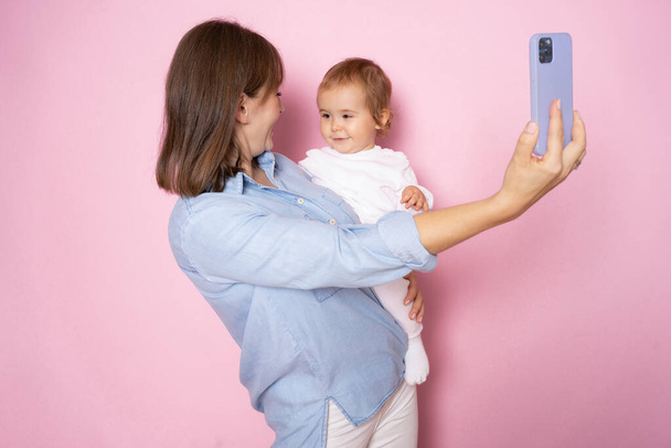 Pembe arka planda izole edilmiş selfie çeken mutlu bir anne ve küçük bir kız.. - Fotoğraf, Görsel