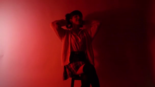 Mladá brunetka žena rytmicky tančí na židli ve studiu   - Záběry, video
