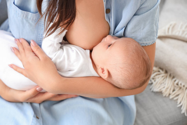 jonge vrouw borstvoeding haar baby thuis, close-up - Foto, afbeelding