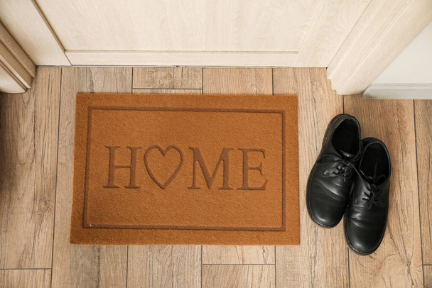 Дверь со словом HOME и обувь на полу, вид сверху - Фото, изображение