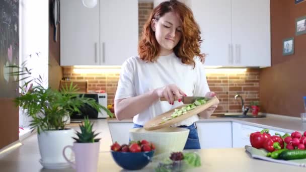 νεαρή καυκάσια γυναίκα κάνει υγιεινές σαλάτες στο σπίτι κουζίνα με λαχανικά και βιολογικά συστατικά γκρο πλαν φόντο. Υγιές πρωινό. Ζωικός τρόπος ζωής - Πλάνα, βίντεο