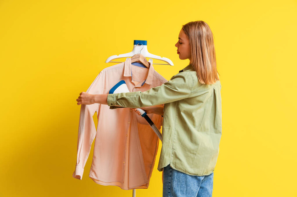 Junge Frau dampfendes Hemd auf gelbem Hintergrund - Foto, Bild