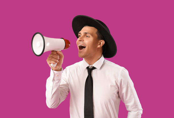 Giovane uomo gridando in megafono su sfondo viola - Foto, immagini