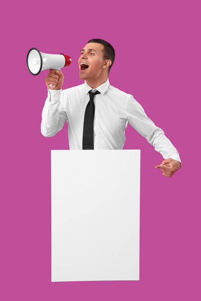Jongeman met lege poster schreeuwen in megafoon op paarse achtergrond - Foto, afbeelding