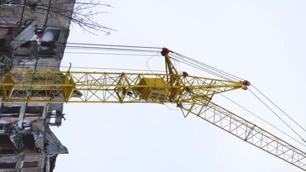 Lange gele torenkraan met lange mast op bouwplaats. Bouwwerkzaamheden op hoogte. Restauratie. - Video