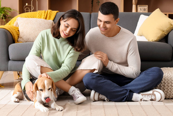 Νεαρό ζευγάρι με χαριτωμένο σκυλί Beagle στο σπίτι - Φωτογραφία, εικόνα