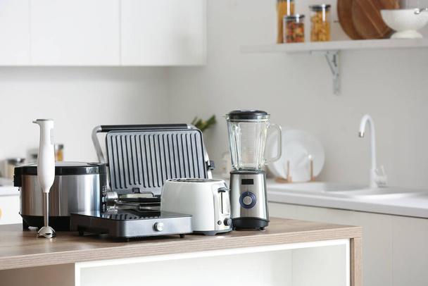 Set moderner Geräte auf Holztisch in zeitgenössischer Küche - Foto, Bild