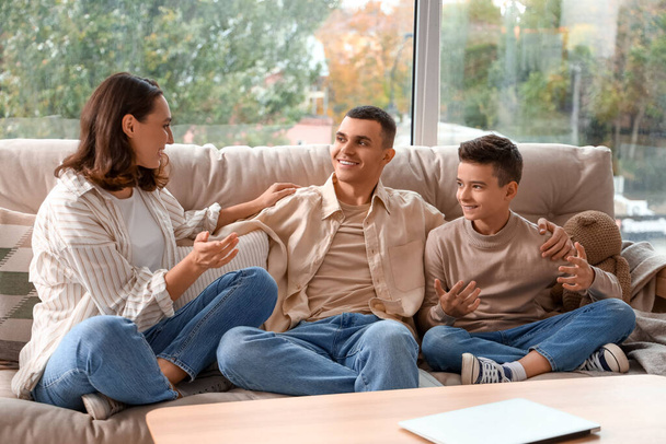 Ragazzino con i suoi genitori seduto sul divano a casa - Foto, immagini