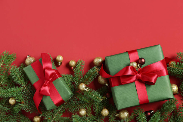 Κουτιά δώρων με κλαδιά χριστουγεννιάτικου δέντρου και μπάλες σε κόκκινο φόντο - Φωτογραφία, εικόνα