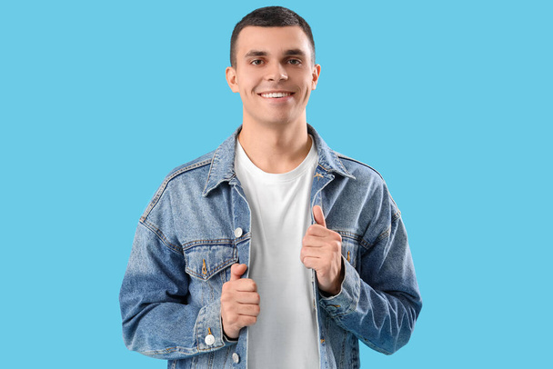 Stilvoller junger Mann in Jeansjacke auf blauem Hintergrund - Foto, Bild