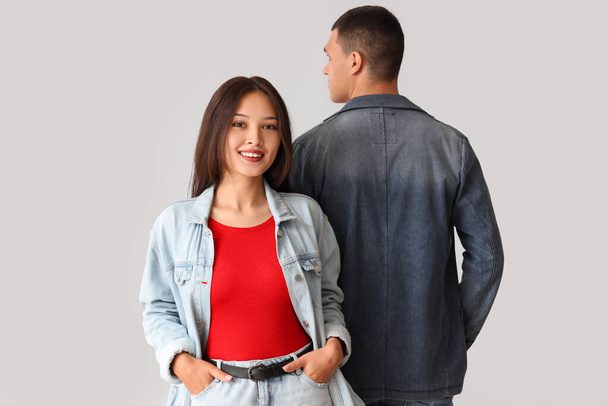 Stylish young couple in denim jackets on light background - Photo, Image